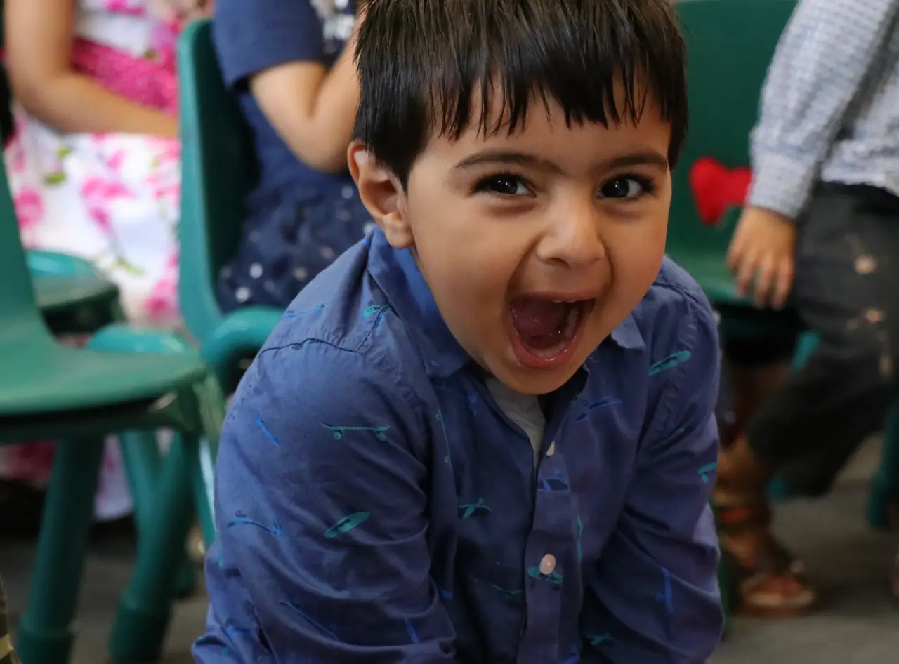 Joyful 4-year-old boy laughs heartily during a hilarious magic show.